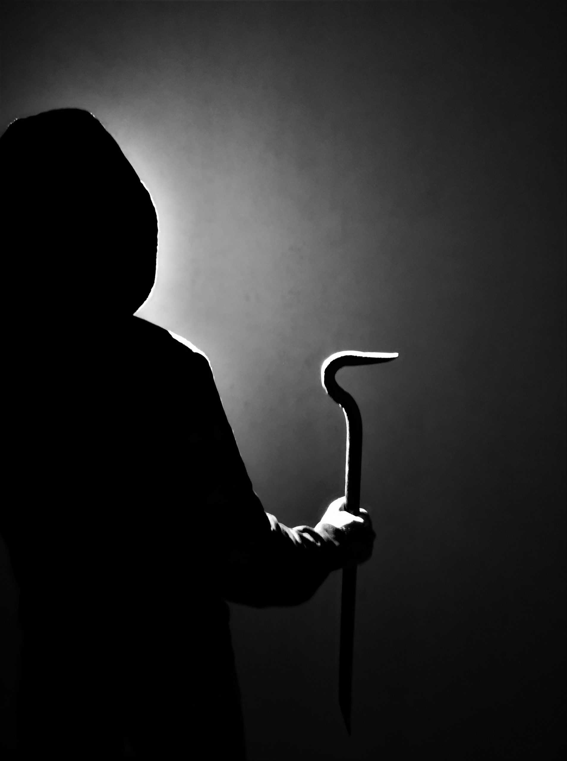 dunkel gekleidete Person, die eine Brechstange in der Hand hält